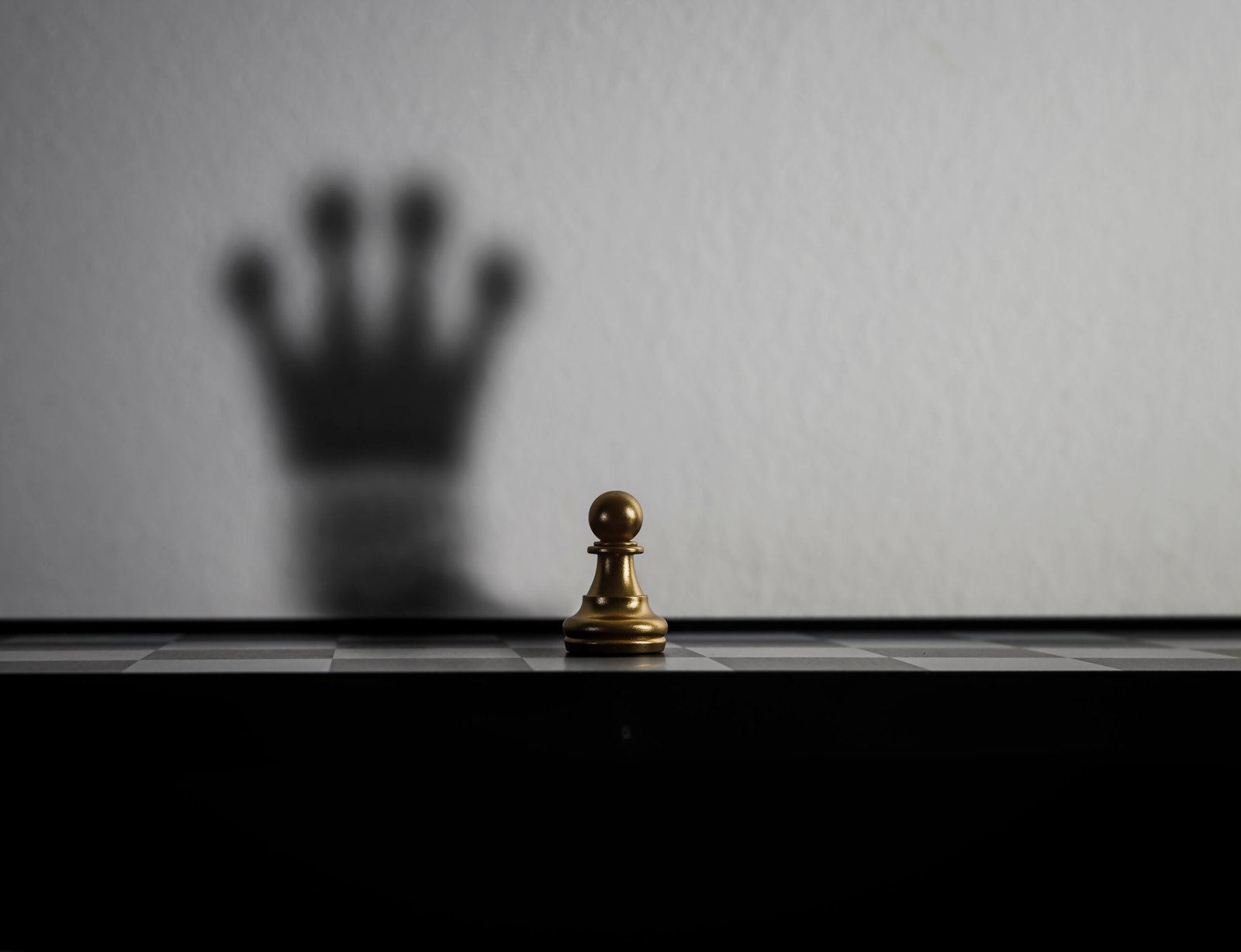 A chess pawn casting a queen’s shadow on a wall, symbolizing business growth, transformation, and strategic potential.
